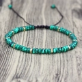Close-up of green striped beads and gold metal spacers on adjustable braided bracelet - Malachite