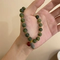 Detailed shot of green stone beads bracelet with gold spacers and hanging charms - Green Round Beads With Pendant
