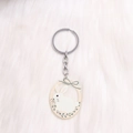 Close-up of cute acrylic white bunny keychain with a floral wreath on plush background - Green Leaf Rabbit