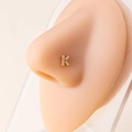 Close-up of a gold-plated initial K nose stud featuring cubic zirconia on a model - Letter K / Gold
