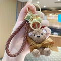 Brown knit-texture resin bear keychain with a woven leather strap and golden bell charm - Sitting Knit Resin Bear-Coffee