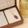 Detail einer goldfarbenen Halskette mit lila Tropfenstein in einer Holz-Schmuckbox - 7# Amethyst Wassertropfen Stil