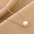 Minimalist pearl necklace with silver chain on textured fabric background - Silver