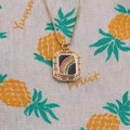 Detailed shot of gold plated rainbow pendant necklace with colorful gemstones on fabric - Black