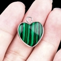 Silver-edged heart pendant with green malachite-style stone held by fingers - Synthetic Malachite Silver Edging