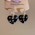 Detailed close-up of golden heart earrings with black enamel and shimmering crystals - Black Heart Hoop