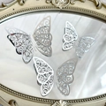 Three silver hollow butterfly cake toppers displayed on a decorative gold-rimmed mirror - Style 1 / Silver