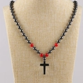 Collar de hematita con cuentas rojas y colgante de cruz negra en un maniquí - Cadena de cuentas redondas magnéticas + Colgante de cruz