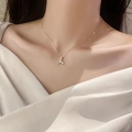 Dettaglio di una collana con pendente a coda di pesce dorata e zirconi sul collo di donna - Catena a Serpente a Coda di Pesce Dorata