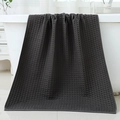 Dark grey waffle weave cotton bath towel draped softly over a white modern bathtub - 70*140cm / Graphite