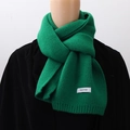 Close-up of green knitted winter scarf with white label detail on a model - Green