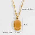 Detail view of a gold beaded chain necklace with an oval orange-pink gemstone pendant - Sunstone