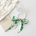 Detail of pearl necklace with a green leaf pattern silk ribbon bow on white background - Green Round Leaf