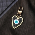 Detail of a heart-shaped evil eye keychain with gold metal frame and resin inlay - Black Heart