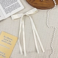 Detail einer cremeweißen Schleifen-Haarspange aus Satin mit langen Bändern - Beige