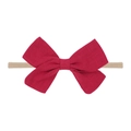 Detail of red fabric bow on skin-tone nylon headband for infants with studio lighting - Red