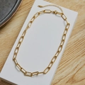 Polished golden paperclip chain necklace with adjustable extender on a white display - Gold