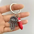 Detailed shot of Hamsa hand charm with red hexagonal stone pendant on key ring - Red Howlite