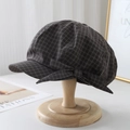 Dettaglio di un berretto a quadri marroni con fiocco decorativo su supporto in legno - Griglia Grigio / M (56-58cm)