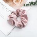 Detail of pink satin scrunchie on a decorative card with blurred floral background - Pink