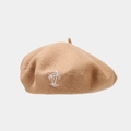 Detailed close-up of white palm tree embroidery on camel wool beret fabric texture - Khaki