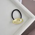Close-up of golden oval alloy hair ring with 5cm by 2.5cm dimensions on white tray - Gold Glossy Oval