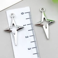 Pendentif étoile en alliage argenté montrant une mesure de 2,5 cm sur une règle - Grand Étoile à Quatre Branches en Croix Creuse / 15x25mm