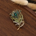 Detail of vintage peacock feather brooch with green zircons on a rustic wood tray - Feather-7 (Antique Gold Green Diamonds Dark Green Gem)