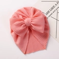 Detail of baby turban hat featuring pink ribbed knit texture and large bow decoration - Watermelon red