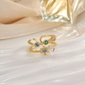 Detail of gold open rings featuring colorful crystals and opal on luxury silk background - Flower Blue Moonstone Look (JZ0121)