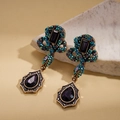 Dettaglio di orecchini pendenti vintage dorati con cristalli viola su sfondo di pietra - Orecchini - Perno in Argento - Viola