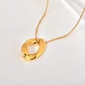 Detail of gold twisted oval pendant with a tiny zircon on white satin fabric background - Gold