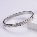 Macro detail of silver nail bracelet featuring sparkling pavé crystals and metallic rivets - Silver