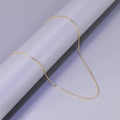 Detail of a shiny gold snake chain necklace draped over a minimalist grey cylinder stand - L27-Round Snake Chain / Gold