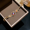 Gros plan détaillé d'un bracelet en zircon rouge ovale doré dans un écrin à bijoux marron - Pierre Rouge Plaquée Or Véritable (18#) / Doré