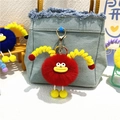 Cute red plush monster keychain with yellow spring tentacles on a blue denim bag - Red