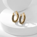 Gold hoop earrings with black pavé zircons displayed on white geometric blocks - Black Zirconia