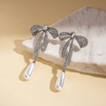 Dettaglio di orecchini a fiocco argentati con strass brillanti e pendente di perla - Orecchini di Perle con Fiocco e Strass (Perno in Argento)