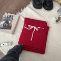 Folded red knit skirt with white bow tie decoration on plush white carpet - Scarf / Red