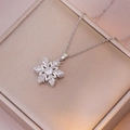 Detailed view of flower pendant necklace with white zircon on champagne jewelry box - X3605 Steel Flower Rotating