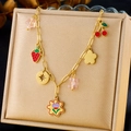 Colorful strawberry and cherry charms on a gold stainless steel necklace over a jewelry box - Strawberry Cherry Star Flower Style (N3142)