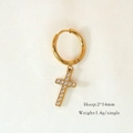 Macro shot of 2x14mm gold cross hoop earring with white zircon on white textured fabric - Zirconia Cross