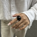 Close-up of a large black resin domed square ring worn on the index finger by a model - Black