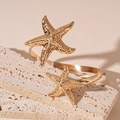 Dettaglio macro del design a stella marina dorata su bracciale rigido aperto stile mare - Oro