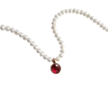 Dettaglio di collana di perle bianche con ciondolo pietra portafortuna rossa in oro rosa - Gennaio Granato