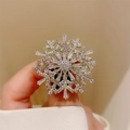 Gros plan d'une bague flocon de neige en argent avec oxydes de zirconium portee - Broche Flocon de Neige Argentée