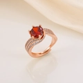 Detailed shot of a rose gold ring with a 3-carat red gemstone and white zircon stones - Rose Gold Red Stone