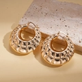 Macro detail of gold-finish quilted texture hoop earrings on natural stone display - Gold