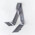 Detail eines grauen Satin-Twilly-Schals mit silbernen Nieten und spitz zulaufenden Enden - Grau
