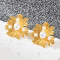 Détails macro de boucles d'oreilles cœur dorées 18k avec perles sur fond texturé chic - Fleur de Perle